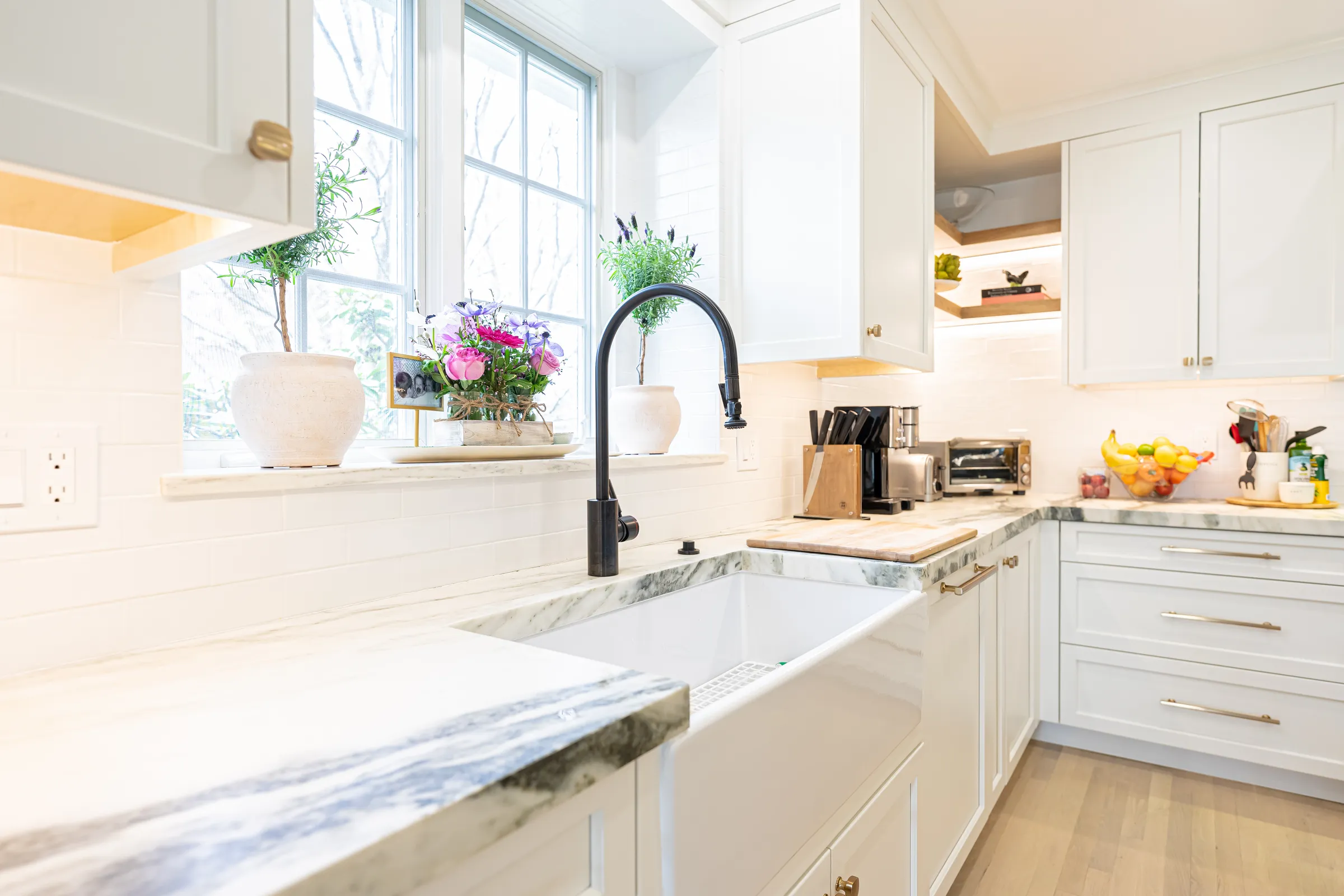 Farmhouse sink set into a quartzite counter beneath a window
